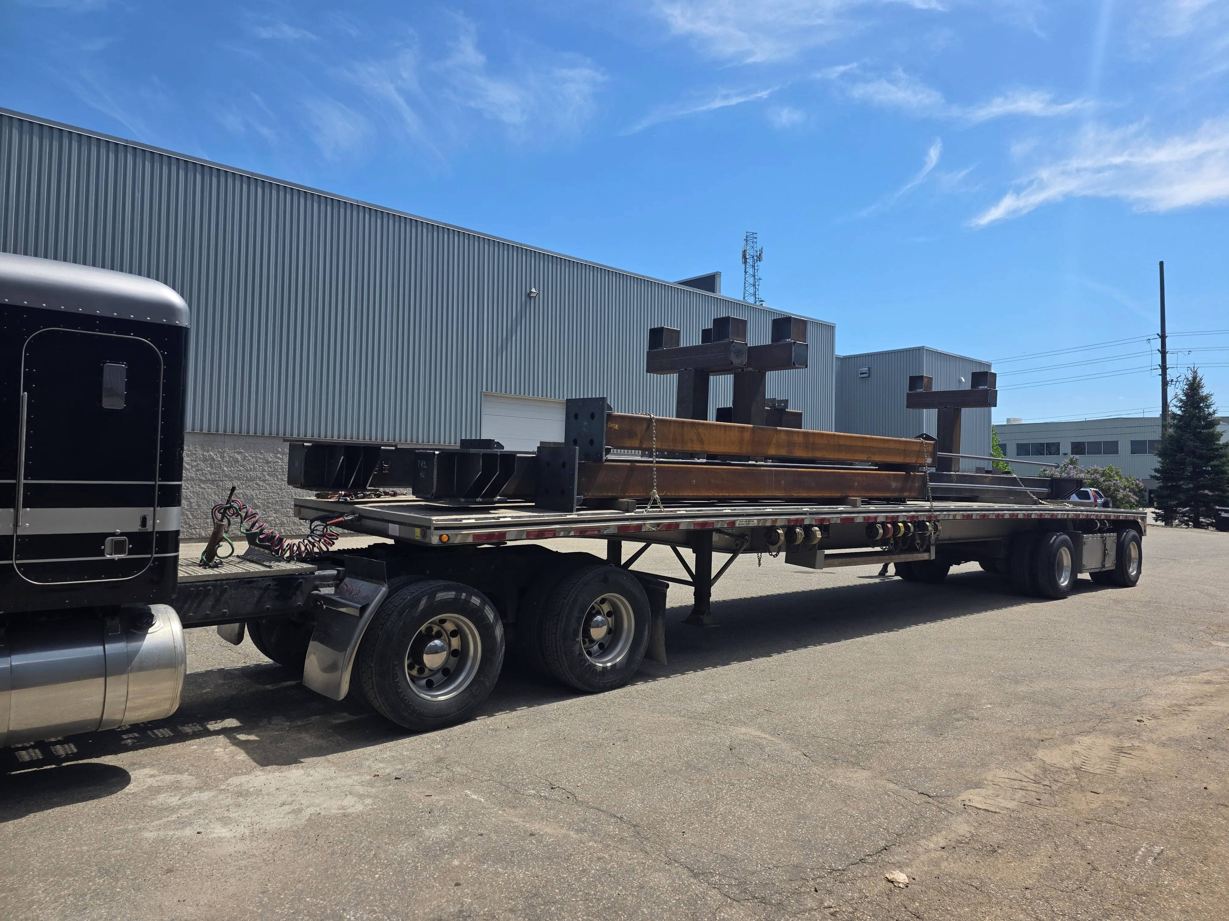 Fabricated structural steel columns and assemblies staged for delivery.